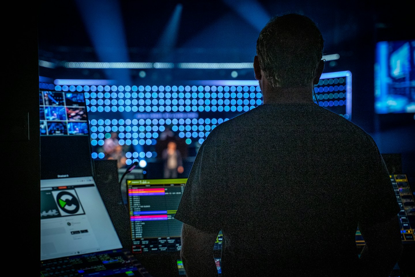 Technician operating a complex control desk with glowing screens.