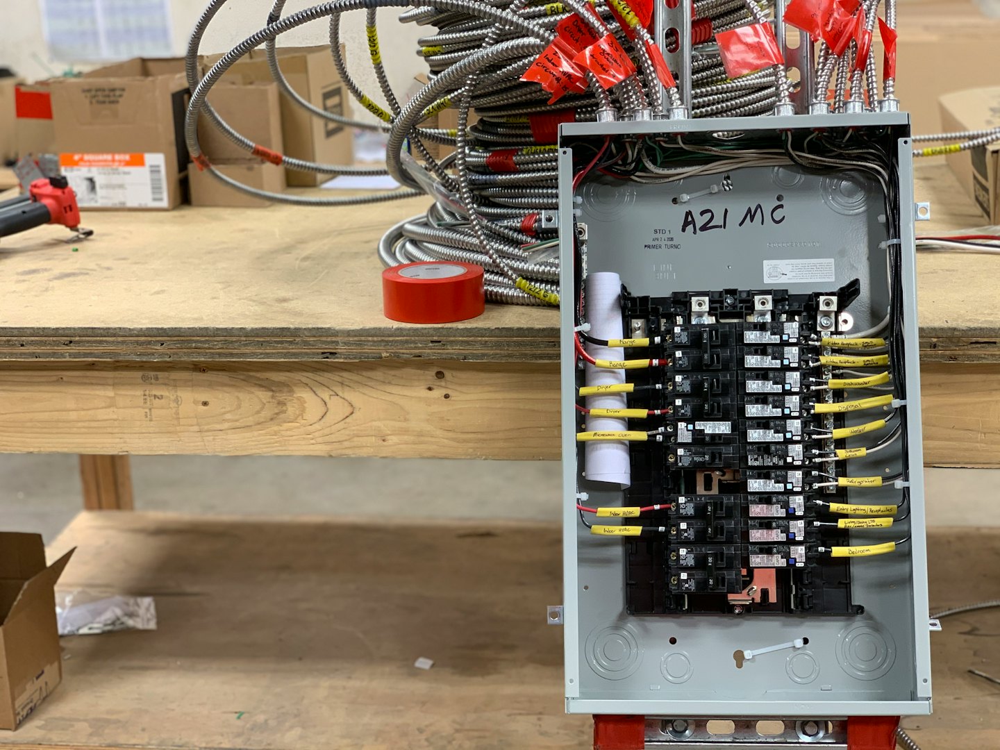 Electrical panel being wired on a workbench with conduits.
